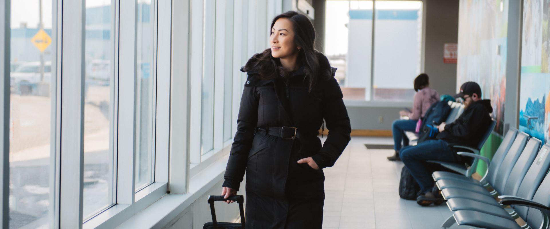 Image shows a women walking with luggage in the airport