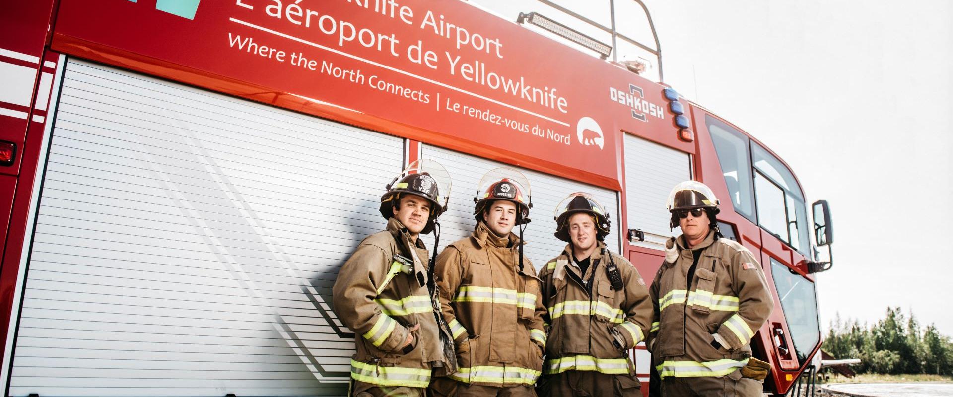 Image show airport firefighers standing in front of a fire truck